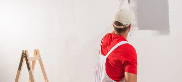 A man painting a mural on a large wall with vibrant colors