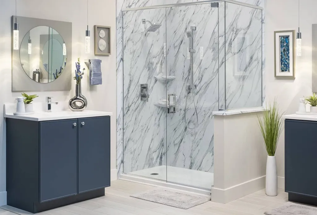 A luxurious bathroom with marble walls, a glass shower, two navy vanities with white countertops, a round mirror, potted plants, and modern pendant lights.