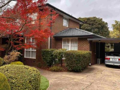 Beautiful front view of a home with newly painted roof and vibrant autumn foliage