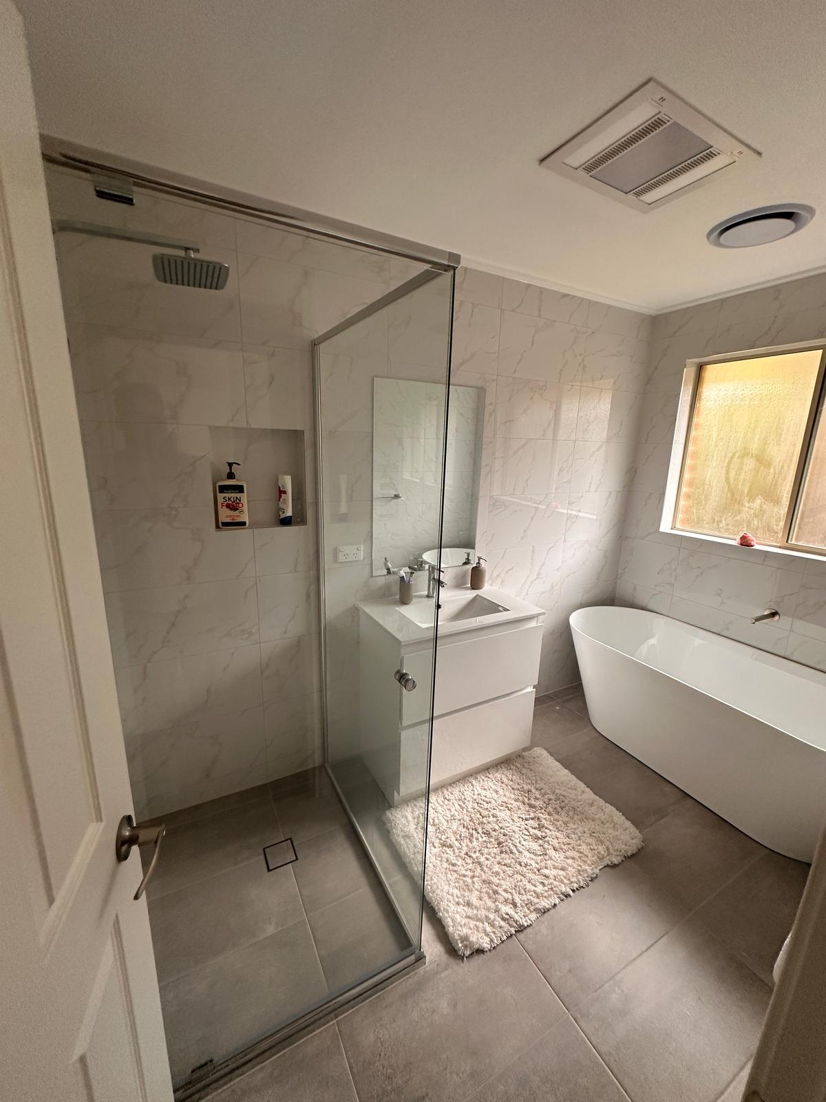 Frameless glass shower with full wall tiling and sleek white vanity in a Deakin Canberra bathroom