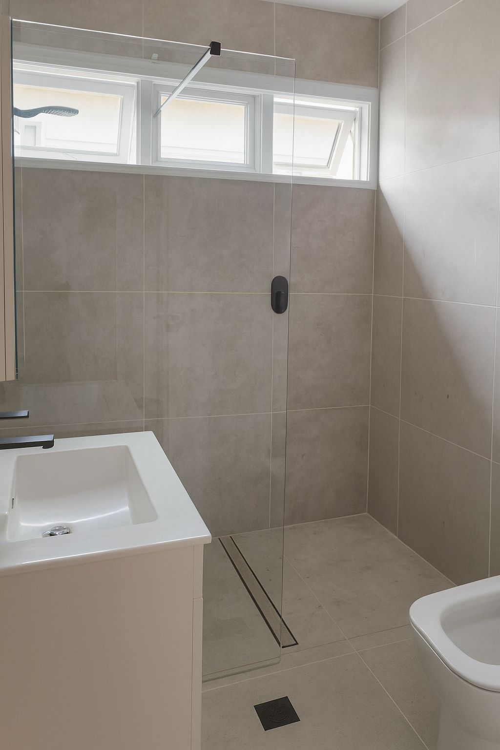 finished bathroom with frameless glass shower and full wall tiling in red hill canberra